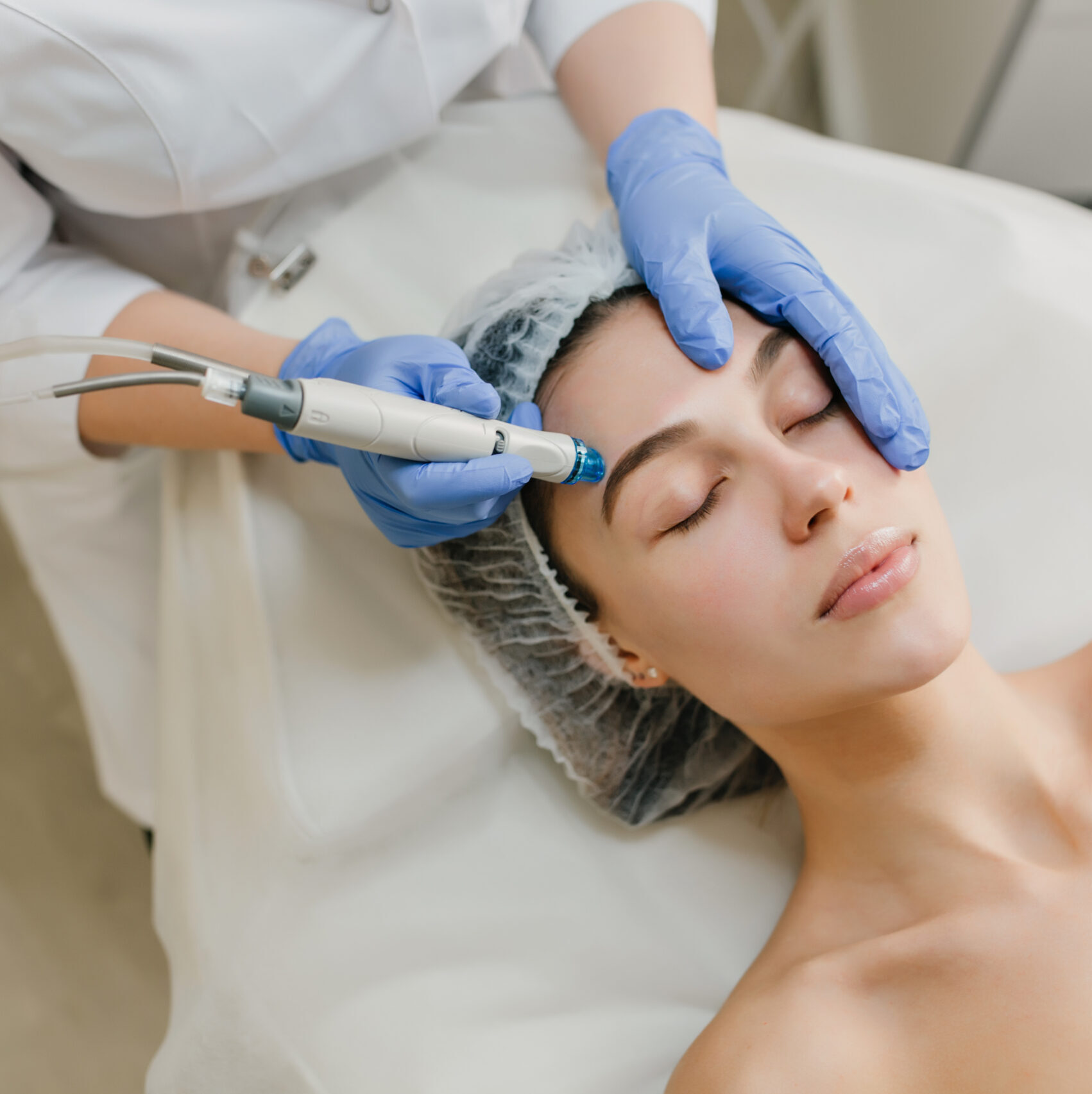 View from above rejuvenation of beautiful woman enjoying cosmetology procedures in beauty salon. Dermatology, hands in blue glows, healthcare, therapy, botox